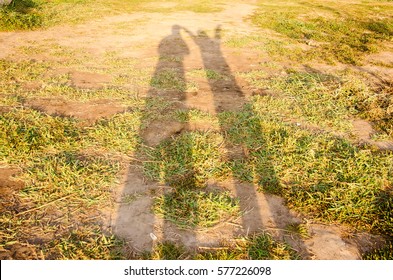 Long shadows of two people taking photos standing on grass lawn with copy space.