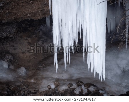 Long sharp icicles hanging from limestone rock overhang at Šikľavá skala near Matejovce nad Hornádom, Slovakia, forming a frozen waterfall in winter landscape.