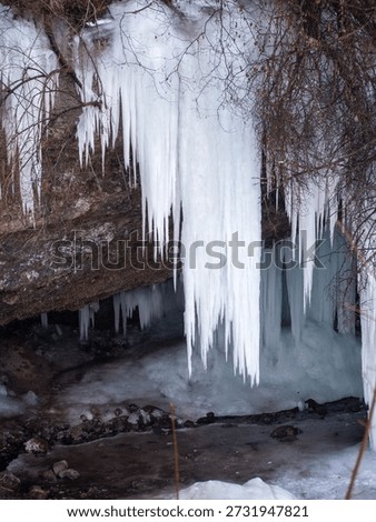 Long sharp icicles hanging from limestone rock overhang at Šikľavá skala near Matejovce nad Hornádom, Slovakia, forming a frozen waterfall in winter landscape.