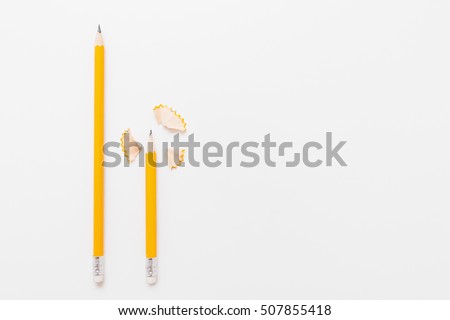 Long and short pencils with shavings on white background, free space for text or advertisement. Top view on two wood pencils with wooden flakes. Chancellery, art, drawing materials, design concept