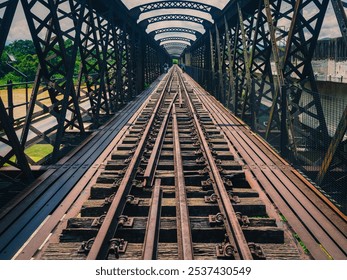 A long shot down the center of a historic Victoria Bridge in Kuala Kangsar,Perak.A railway bridge with multiple tracks and a wooden walkway,spans a river valley with lush green trees in the background - Powered by Shutterstock