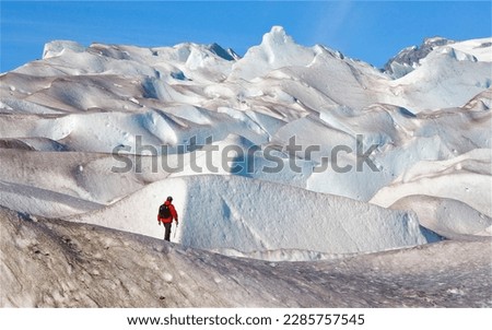 Long shot of male ice hiker in red jacket shot from behind on Mendenhall Glacier, Juneau, Alaska