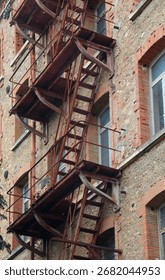 long solid iron fire escape stairs on the exterior of an old century-old building with red face-brick
