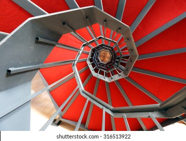 long spiral staircase with red carpet in a modern building - Powered by Shutterstock