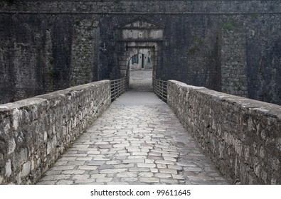 The long stone bridge and narrow semicircular gate on a fortification. Montenegro.