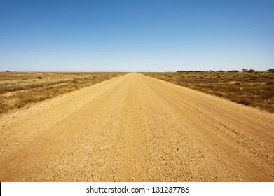 A long, straight dirt road disappears into the distant horizon.