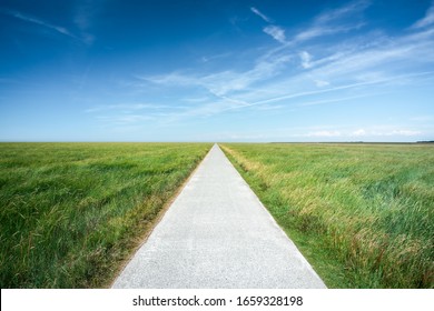 Long straight road along grassland