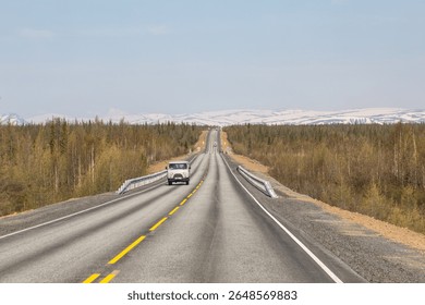 A long straight road cuts through the polar taiga. A 