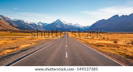 A long straight road leading towards a snow capped mountain in New Zealand