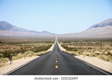 A long straight road in the middle of the Nevada desert
