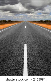 Long Straight Road In Western Australia With Gathering Storm Clouds Overhead. Concepts Of Trouble Ahead And Finding A Way Through. Road Is Symmetrical Has Been Mirrored.