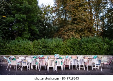 Long Table And Chairs With Mixed Upholstery Outside On The Courtyard Waiting For A Group Of Friends On Holidays To Populate Them. Concept For Team Building, Friendship Or Togetherness.