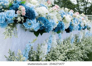 A long table decorated with artificial flowers, dominated by blue and white, decorated the white surface covered with lace. decoration for wedding - Powered by Shutterstock - Get 15% off with code: PIKWIZARD15
