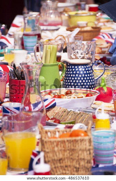 Long table of party food and drink from a street\
party in Great Britain.