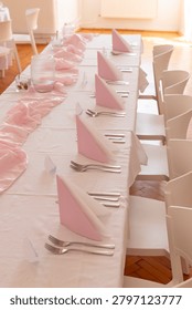 Long table prepared for a celebration with pink napkins and white tablecloth