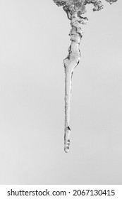 a long thin icicle on a gray sky background, black and white photo