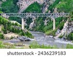 Long  train bridge extends over river in the remote mountain area of Alaska.