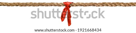 Long tug of war rope pulled tight, with red ribbon tie. Concept of conflict, competition, or rivalry. Isolated on white.