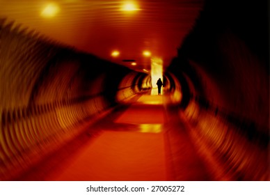 Long tunnel with dramatic lighting and person's silhouette.  Radial blur effect applied.