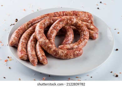 long uncooked meat sausages, Raw thin long chicken sausages on white dish for grilling - Shutterstock ID 2122839782
