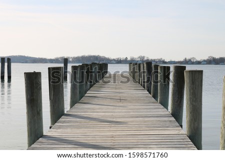 Long weathered wooden dock pier in coastal seaside harbor beach in winter