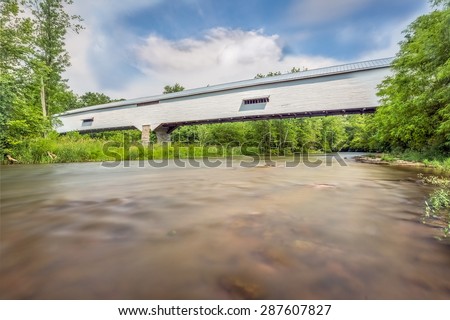 The long white historic covered bridge at Moscow, Indiana spans the Flatrock River in Rush County.