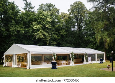 Long white tent for wedding party in the woods.