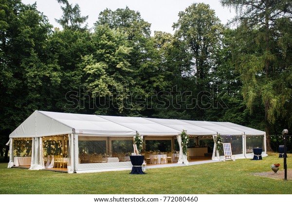Long white\
tent for wedding party in the\
woods.