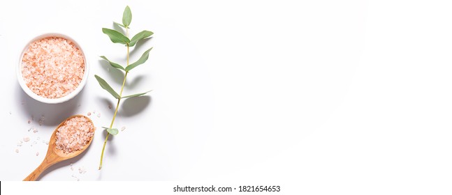 Long wide banner with organic Himalaya salt and twig of fresh aromatic eucalyptus on white background. Spa and wellness concept. Minimalism style composition.