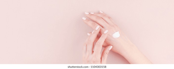 Long wide banner of woman moisturizing her hand with cosmetic cream lotion with copy space on millennial pink background minimalism style. Concept template feminine blog, social media, beauty concept - Powered by Shutterstock