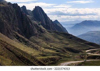 A Long Winding Mountain Road, Against The Backdrop Of High Relief, Sharp Mountains.