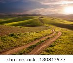 a long and winding rural path crosses the hills at the sunset
