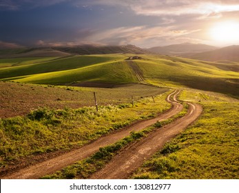 ein langer und kurvenreicher ländlicher Weg durch die Hügel bei Sonnenuntergang