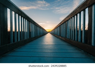 A long wooden boadwalk seems to stretch to infinity. Walkway leading to the sky at sunset, concept, copy space for the text - Powered by Shutterstock