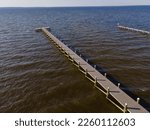 Long wooden pier to a dock with wood pillars at Navarre, Florida. Aerial shot view of a private docks on an ocean waterfront against the skyline background.