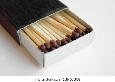 Long wooden safety matchsticks stacked in cardboard matchbox on white background.