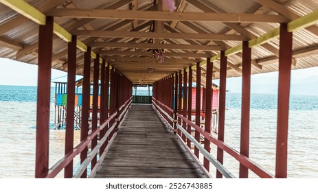 A long wooden walkway with a view of the ocean. The walkway is lined with colorful houses and a bridge - Powered by Shutterstock