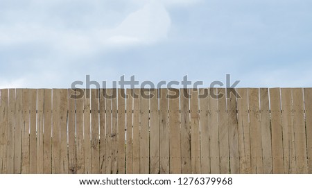Long wooden wall block the tree have blue sky and white cloud background.Have space for text.