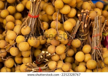 Longan fruit close-up as a background. The Dragon Eye Harvest is in a pile on the counter. Fresh tropical fruits. Dimocarpus longan, Central Thailand