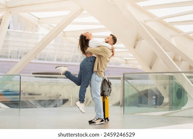 Long-Awaited Reunion. Romantic Young Couple Embracing At Airport After Arrival, Living Man Lifting Up His Girlfriend In Air While Standing Together At Terminal Hallway, Full Length With Copy Space - Powered by Shutterstock