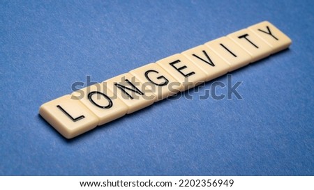 longevity word in ivory letter tiles against textured handmade paper, lifespan and healthspan concept