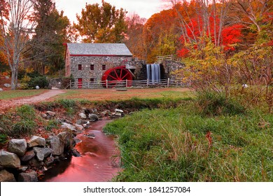Longfellow's  Wayside Inn Grist Mill with water wheel and cascade water fall in Autumn at sunrise, Sudbury Massachusetts USA
