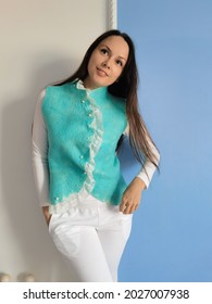 A Long-haired Brunette Poses In Front Of The Camera In A Vest. Turquoise Jacket, Handmade, Piled From Merino Wool.