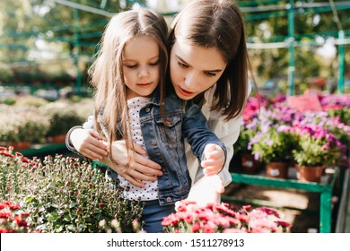 Long-haired child enjoying gardening with mother. Woman working in greenhouse. - Powered by Shutterstock