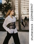 long-haired girl in a black corset and white shirt on the street
