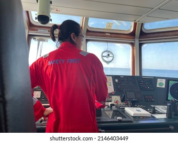 a long-haired male sailor wearing a red coverall was piloting the ship, maneuvering the ship to dock. a seafarer under controlling vessel due to maneuver for alongside at jetty - Shutterstock ID 2146403449