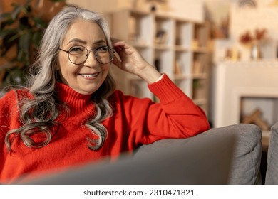 Long-haired woman in red at home and feeling positive - Shutterstock ID 2310471821