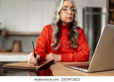 Long-haired woman in red at home working at the laptop - Shutterstock ID 2310471823