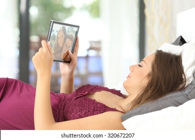 Longing Woman Looking A Picture Of Her Boyfriend In A Frame On The Bed At Home