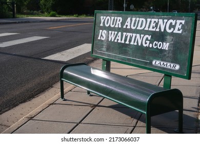 Longmont, CO USA - June 23, 2022: Lamar advertising poster on a green bus stop bench. Your audience is waiting.